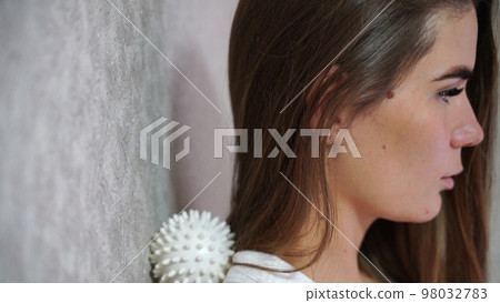 Athletic slim caucasian woman doing thigh self-massage with a massage ball indoors. Self-isolating massage Athletic slim caucasian woman doing thigh self-massage with a massage ball indoors. Self-isolating massage 98032783