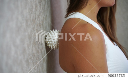 Athletic slim caucasian woman doing thigh self-massage with a massage ball indoors. Self-isolating massage Athletic slim caucasian woman doing thigh self-massage with a massage ball indoors. Self-isolating massage 98032785