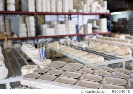 Shelves with unfinished ceramic dishware in pottery factory 98034048