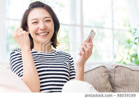 A woman looking at her smartphone smiles A woman looking at her smartphone smiles 98039199