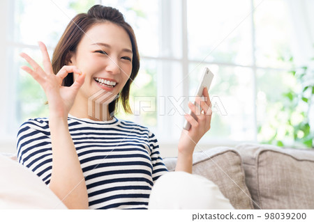 一個女人看著她的智能手機微笑 一個女人看著她的智能手機微笑 98039200