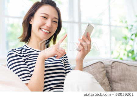 A woman looking at her smartphone smiles A woman looking at her smartphone smiles 98039201