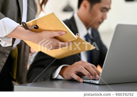 Attractive young Asian female secretary or assistant noting something on her notebook 98039292