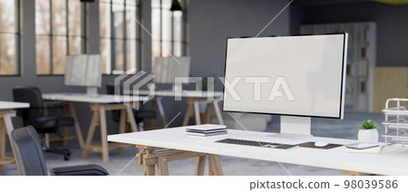 Blank screen of a computer mockup with office supplies on a desk in modern company office room. 98039586