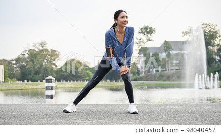 Healthy Asian female runner in sportswear stretching her legs and knees 98040452