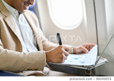 Successful Asian businessman manages his business financial paperwork on the flight. close-up 98040659