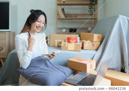 Starting small business entrepreneur of independent young Asian woman online seller is using computer and taking orders to pack products for delivery to customers. SME delivery concept. Starting small business entrepreneur of independent young Asian woman online seller is using computer and taking orders to pack products for delivery to customers. SME delivery concept. 98042236