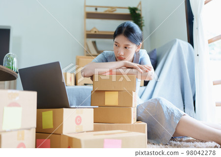 Starting small business entrepreneur of independent Asian woman showing her face worried about the sales of her business not reaching the target set. SME concepts. 98042278