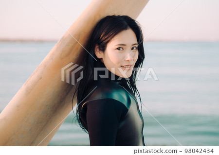 A young woman who enjoys surfing 98042434