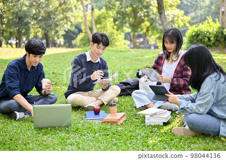 Happy young Asian college students relaxing in the campus's park, working their group project Happy young Asian college students relaxing in the campus's park, working their group project 98044136
