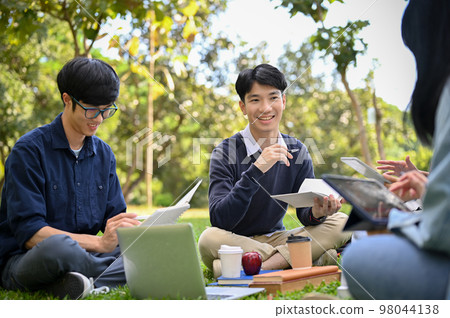 Happy young Asian male college student is having a great time with his friends in the campus's park Happy young Asian male college student is having a great time with his friends in the campus's park 98044138
