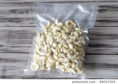Vacuum-packed dried cashews on a wooden background. Plant-based diet, healthy fats, keto diet, lchf 98045304