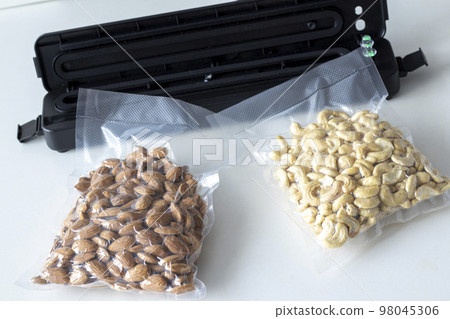 Vacuum packaging of almonds and cashew nuts for long term storage. Use vacuum packer for long term storage of products. Vacuum packaging machine in the home kitchen. Vacuum packaging of almonds and cashew nuts for long term storage. Use vacuum packer for long term storage of products. Vacuum packaging machine in the home kitchen. 98045306