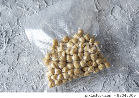 Hazelnuts in a plastic vacuum bag on a gray textured background. Hazelnuts in a plastic vacuum bag on a gray textured background. 98045309