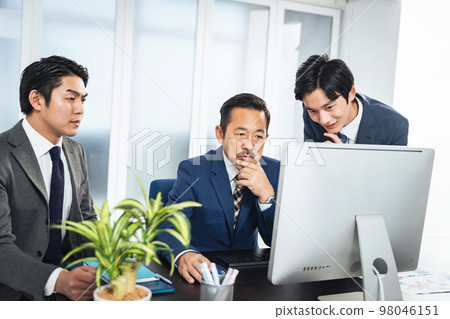 一群商務人士一邊看電腦屏幕一邊開會 98046151