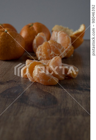 Slice of tangerines on a wooden surface Slice of tangerines on a wooden surface 98046392