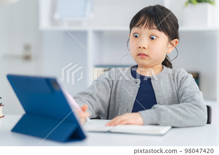 Surprised girl looking at a tablet Online class Surprised girl looking at a tablet Online class 98047420