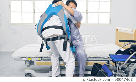 一位穿著動力輔助服的護士抱著病人轉移輔助設備 一位穿著動力輔助服的護士抱著病人轉移輔助設備 98047468