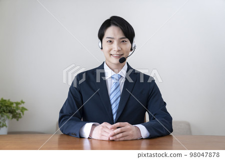 Young man in suit looking at camera wearing headset Young man in suit looking at camera wearing headset 98047878