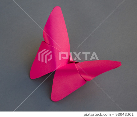 Pink paper butterfly origami isolated on a grey background Pink paper butterfly origami isolated on a grey background 98048301