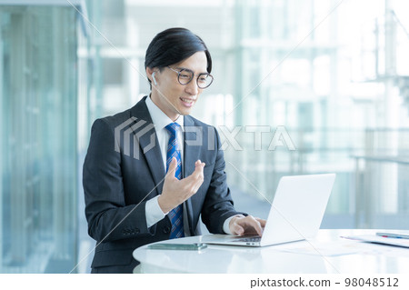 一位戴著眼鏡的商人正在打視頻電話 一位戴著眼鏡的商人正在打視頻電話 98048512