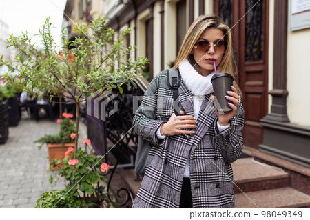 woman tourist with a cup of coffee on the background of a beautiful street woman tourist with a cup of coffee on the background of a beautiful street 98049349