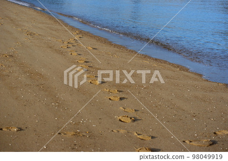沙灘海景與腳印和海灘與碰撞的波浪和藍色海面 沙灘海景與腳印和海灘與碰撞的波浪和藍色海面 98049919