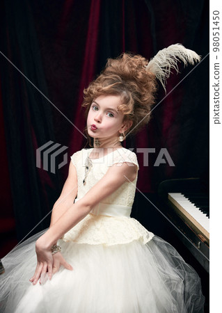 Portrait of cute little girl, child in image of medieval royal person in fabulous dress sitting and posing with lovely face Portrait of cute little girl, child in image of medieval royal person in fabulous dress sitting and posing with lovely face 98051450