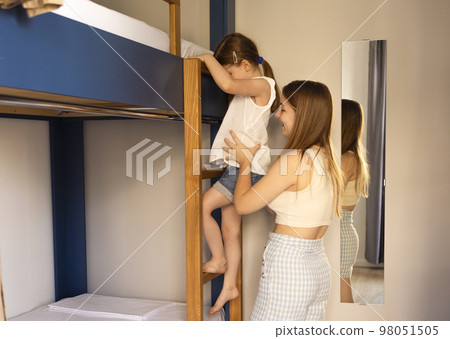 Caucasian siblings by bunk bed. Older sister helping. 98051505