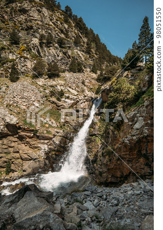 Small mountain river in the valley of Vall de Nuria Spain is gaining strength at the top of the Pyrenees. The channel of clear cold water moves down with unrestrained pressure along a gentle slope. 98051550