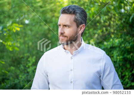 Handsome manager man in white shirt looking aside natural background Handsome manager man in white shirt looking aside natural background 98052133