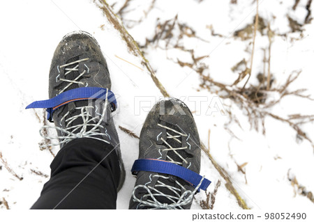 Female climber wearing simple crampons Female climber wearing simple crampons 98052490