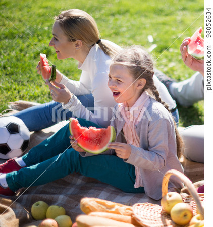 Father, mother, daughter and son enjoy eating watermelon at picnic in park in summer Father, mother, daughter and son enjoy eating watermelon at picnic in park in summer 98052634