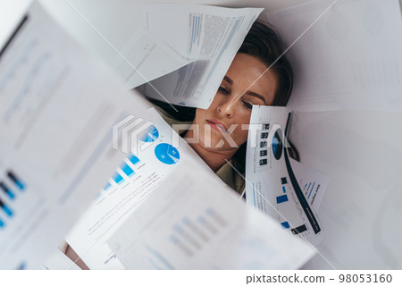 A woman lying covered in papers 98053160