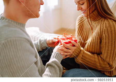 Valentine's Day concept. Exchange of gifts. Young couple at home celebrating Valentine's Day. Valentine's Day concept. Exchange of gifts. Young couple at home celebrating Valentine's Day. 98053951
