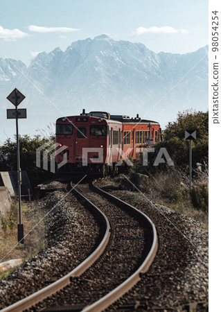 The Tateyama mountain range in the background with the train turning an S-curve 98054254
