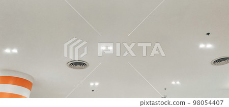 Ceiling mounted cassette type air conditioner and modern lamp light on white ceiling. Duct air conditioner for home, hall or office. 98054407