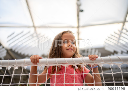 Little girl lean on net looking away 98055396