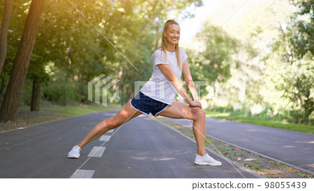 Woman runner stretching legs Woman runner stretching legs 98055439