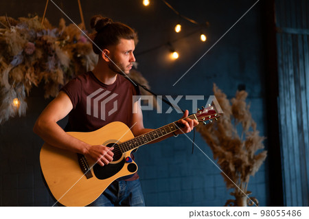 Handsome young man playing acoustic guitar Handsome young man playing acoustic guitar 98055486