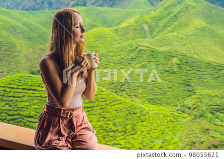 Young woman Drinking Healthy Green Tea against a tea plantation. Healthcare or Herbal medicine concept Young woman Drinking Healthy Green Tea against a tea plantation. Healthcare or Herbal medicine concept 98055621