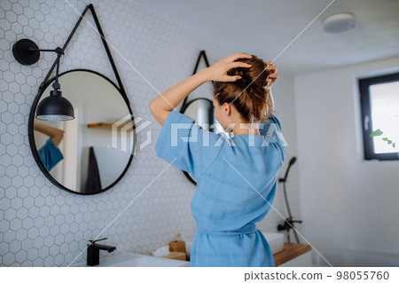 Young woman taking care of her hair, morning beauty routine concept. 98055760