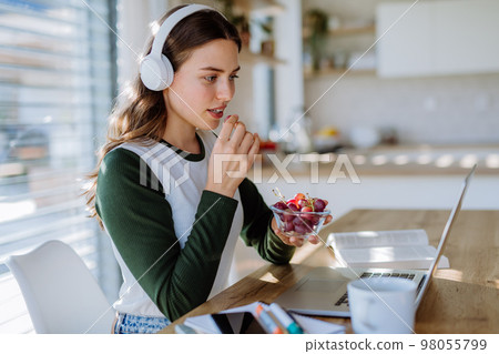 Young woman having distance education in her apartment. 98055799