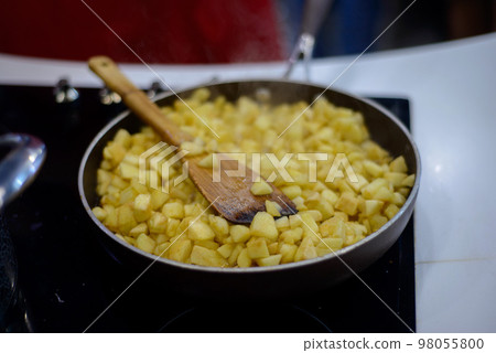 finely chopped apples are fried in sugar on a black frying pan 98055800