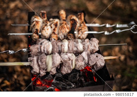 shish kebab, pieces of meat with onion rings on skewers fry in charcoal grills shish kebab, pieces of meat with onion rings on skewers fry in charcoal grills 98055817