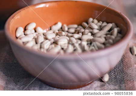 White beans in a clay deep plate on a linen tablecloth, soft focus White beans in a clay deep plate on a linen tablecloth, soft focus 98055836