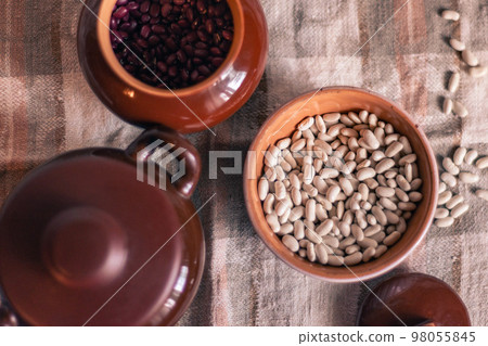 White beans in a clay deep plate on a linen tablecloth among clay pots, soft focus White beans in a clay deep plate on a linen tablecloth among clay pots, soft focus 98055845