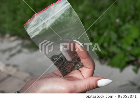 a plastic bag of synthetic smoking substances and Marijuana Cannabis Joint  in the hand of a smoker 98055871