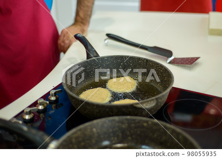 in the kitchen on a black frying pan are grilled small pancakes or cutlets in the kitchen on a black frying pan are grilled small pancakes or cutlets 98055935