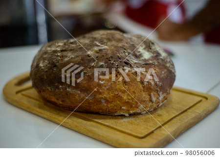 round black bread with ruddy crust on a wooden board in the kitchen 98056006